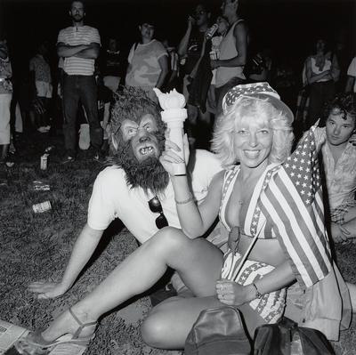 [woman in stars and stripes outfit with man in werewolf mask]