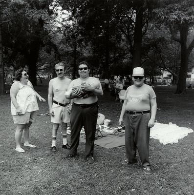 [three men, one holding a baby doll in a plastic bag, and one woman]